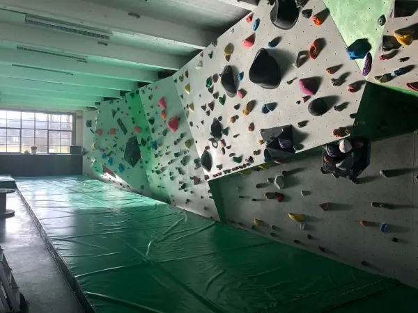 Long overhanging wall covered in holds above green matting
