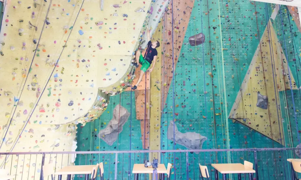 Climber on a rope beside the overhanging bulge, above the bar's mezzanine tables