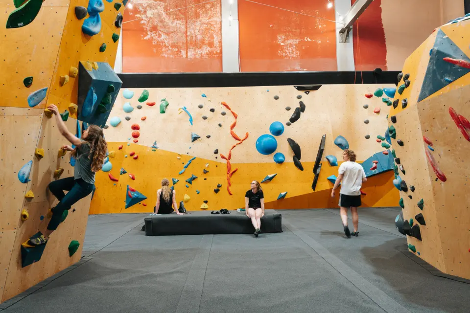 Climbers on yellow walls around a padded bench, with the theatre's orange walls above