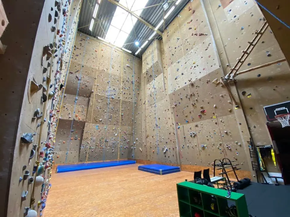 The climbing hall with crash mats and training equipment in the corner