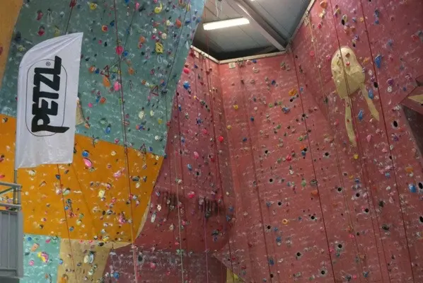Tall roped walls in pink, green and yellow, with an overhang and a wave-shaped section