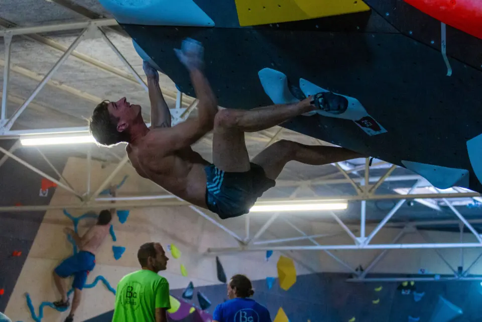Climber with feet off on a steep overhang while others watch from below