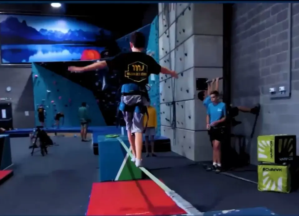 Slackline, bouldering wall and rope walls under a mountain mural in the hall