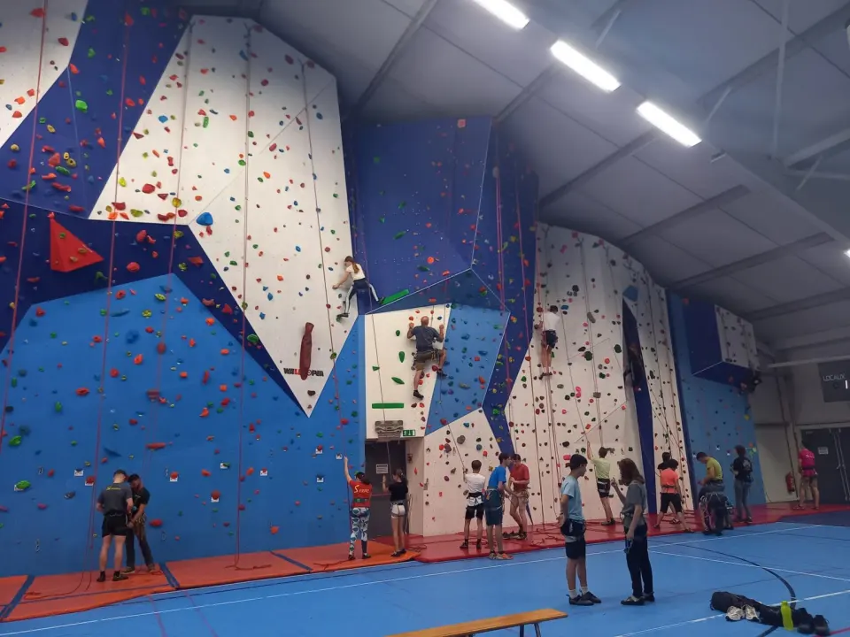 Climbers on the blue and white roped walls of the Mosa sports hall