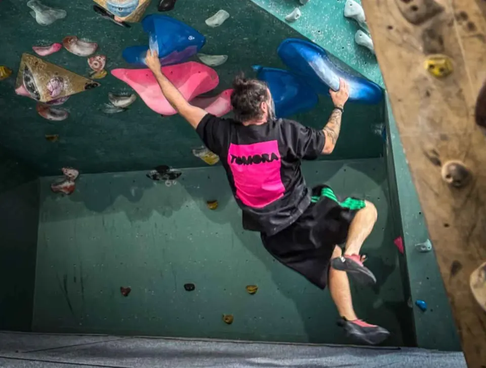Climber pulling through the overhang on blue and pink volumes