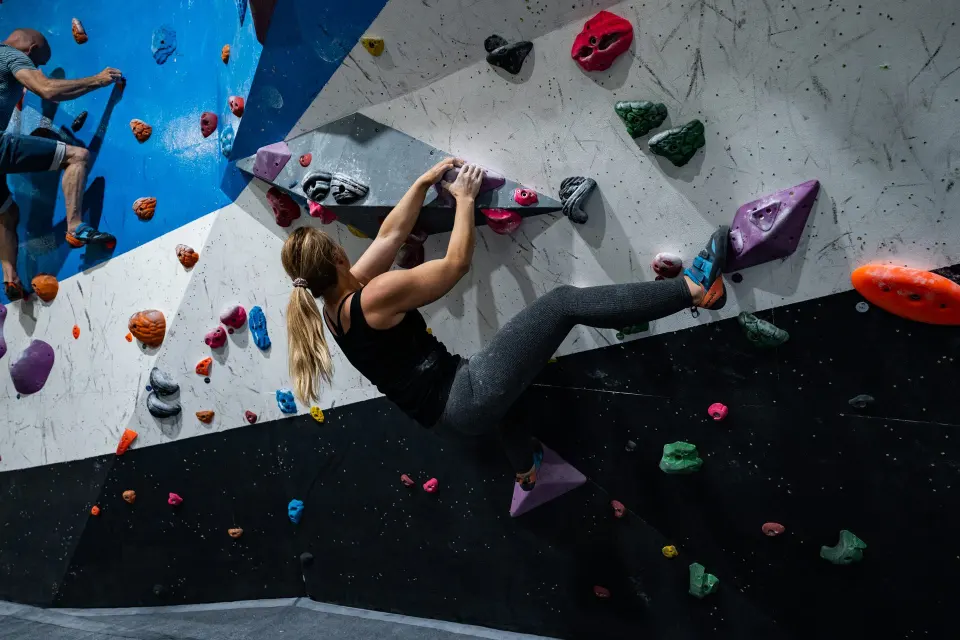 Climber on an overhanging section of the blue and white bouldering wall