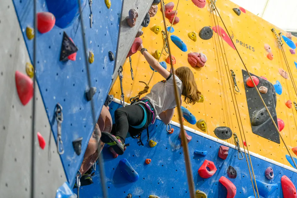 Climber high on the yellow wall on a top rope