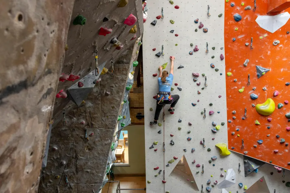 Climber halfway up a grey route next to the textured rock-effect wall