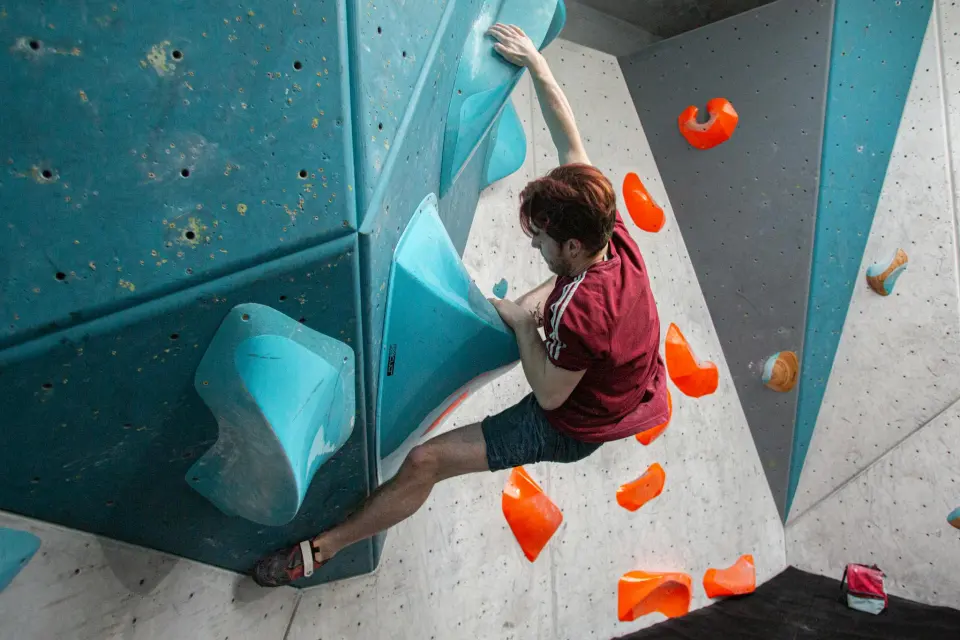 Boulderer on teal volumes in the bouldering area