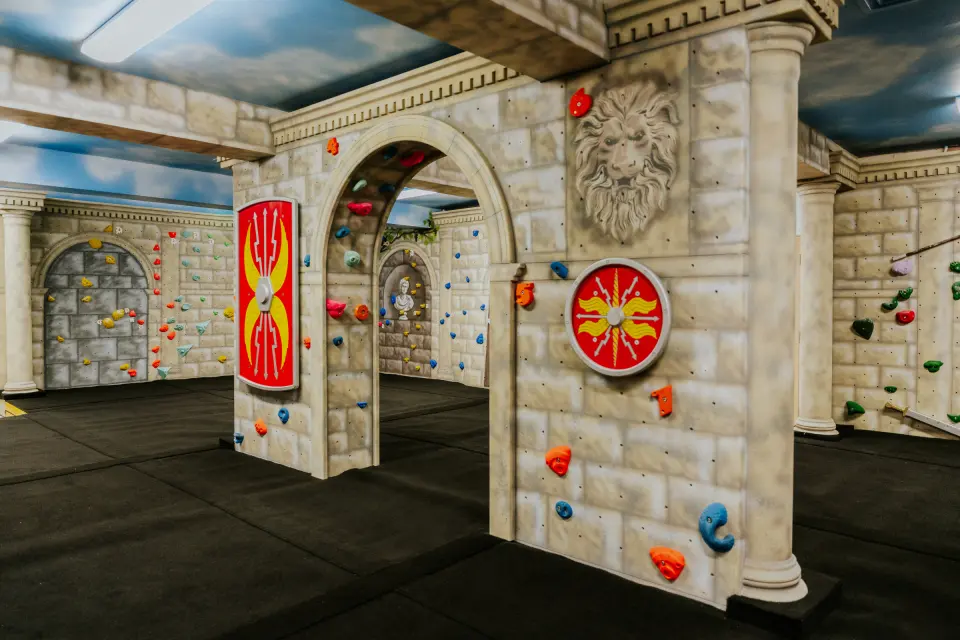 Roman-themed children's climbing room with arches and shields