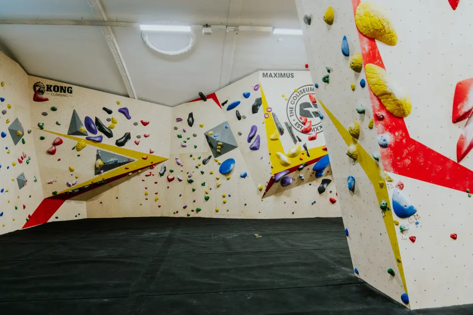 Angled bouldering walls with volumes and red and yellow trim