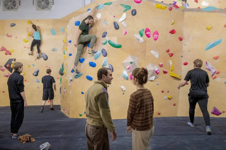 Climbers on the bouldering walls with volumes and padded matting