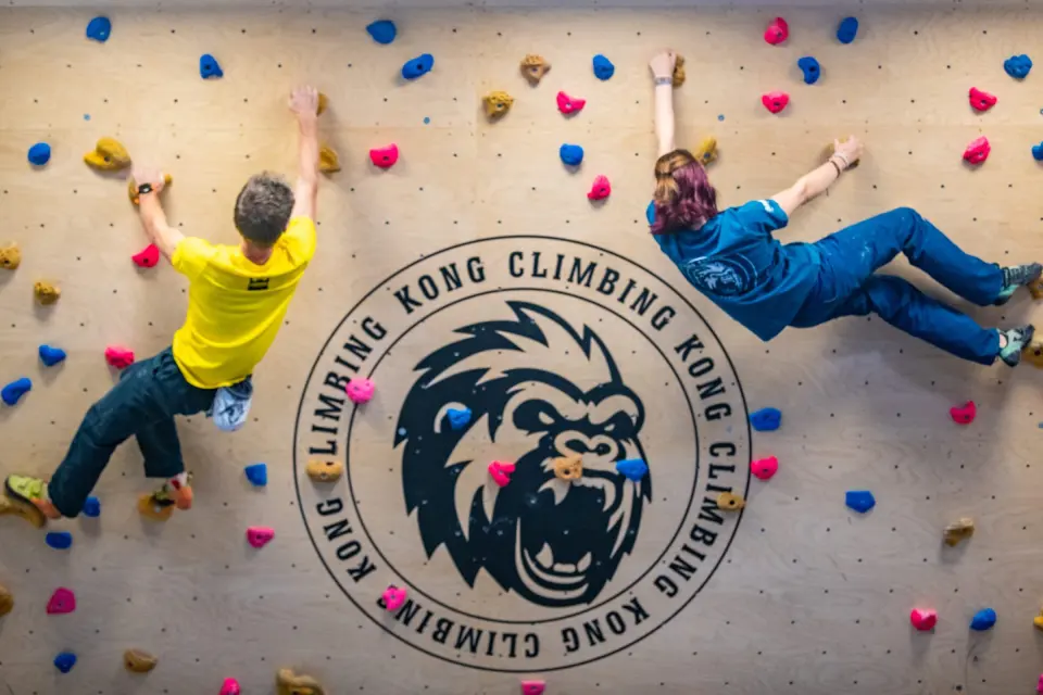 Two climbers on the bouldering wall above the Kong logo