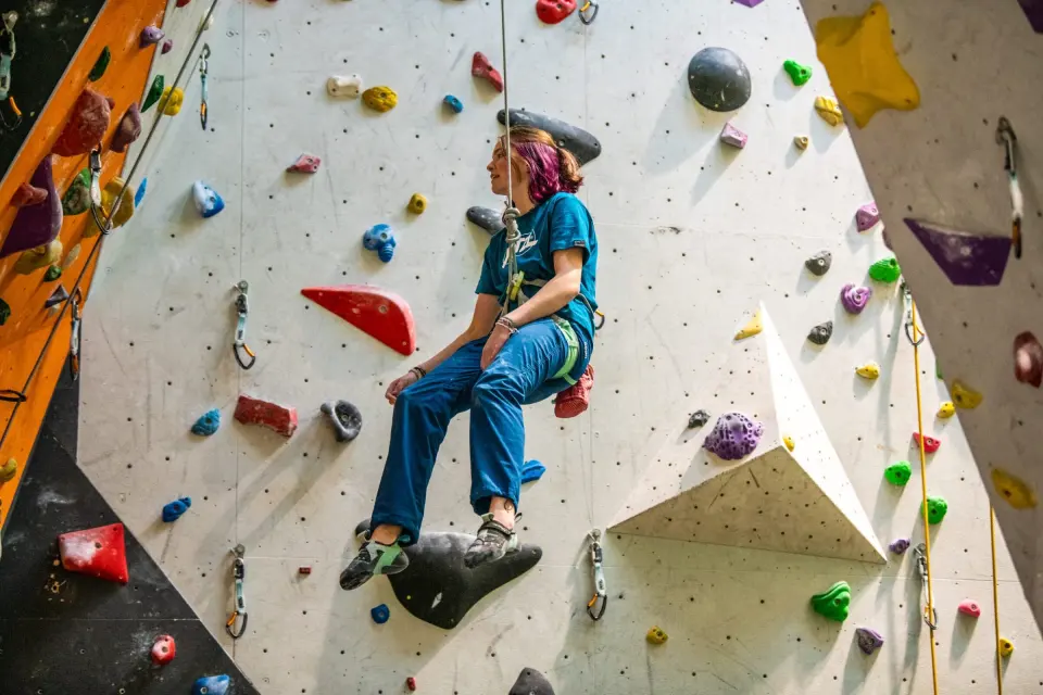 Climber resting on a rope beside a white volume