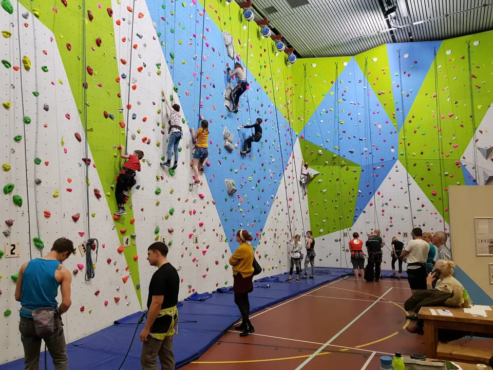 Climbers on the blue, green and white roped wall in the sports hall