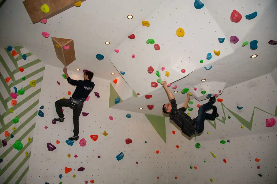 Two climbers bouldering under a hanging fin