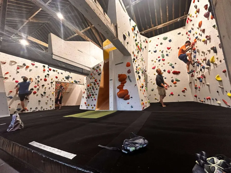Bouldering hall under the mill's timber roof, with climbers on the walls