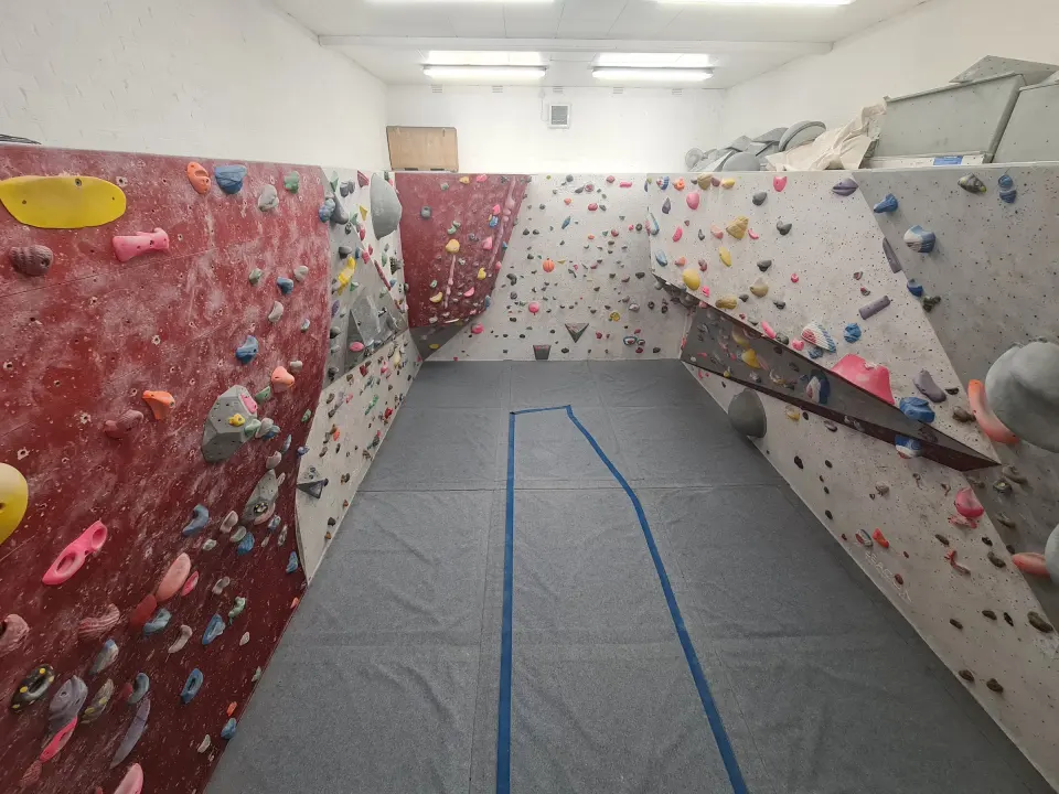 The bouldering room with angled walls and grey matting