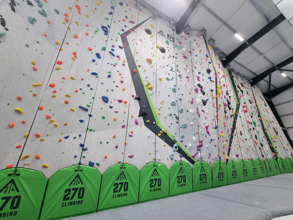 Row of tall indoor lead and auto-belay walls in the main roped hall