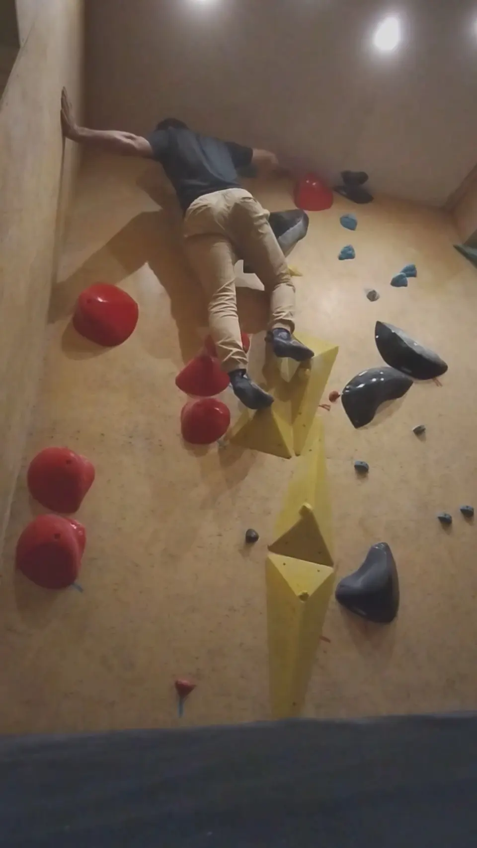 Climber bridging between walls on a problem with yellow volumes