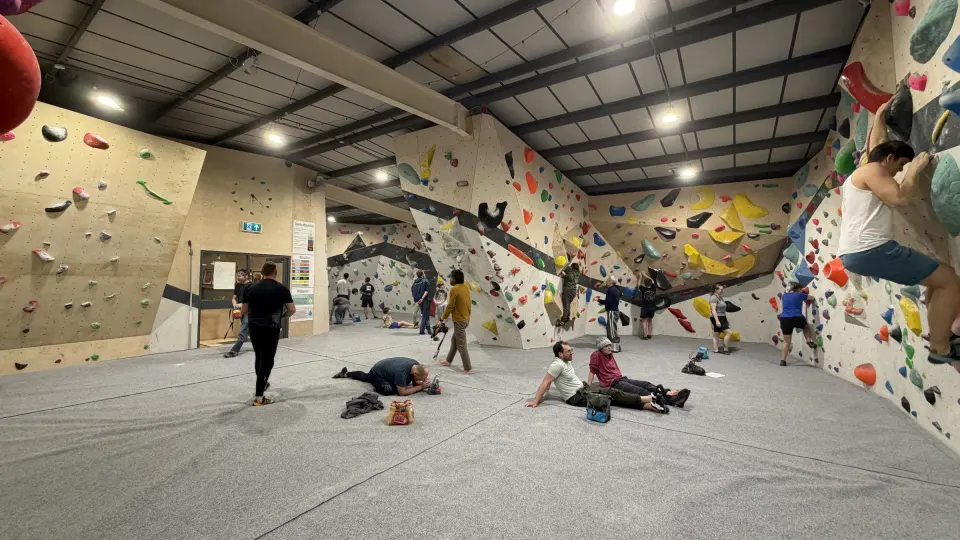 The bouldering hall with climbers on the walls and resting on the matting