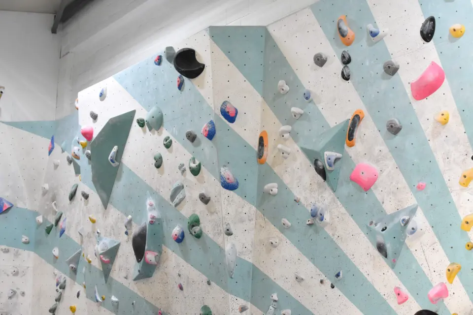 Teal and white striped bouldering wall with volumes