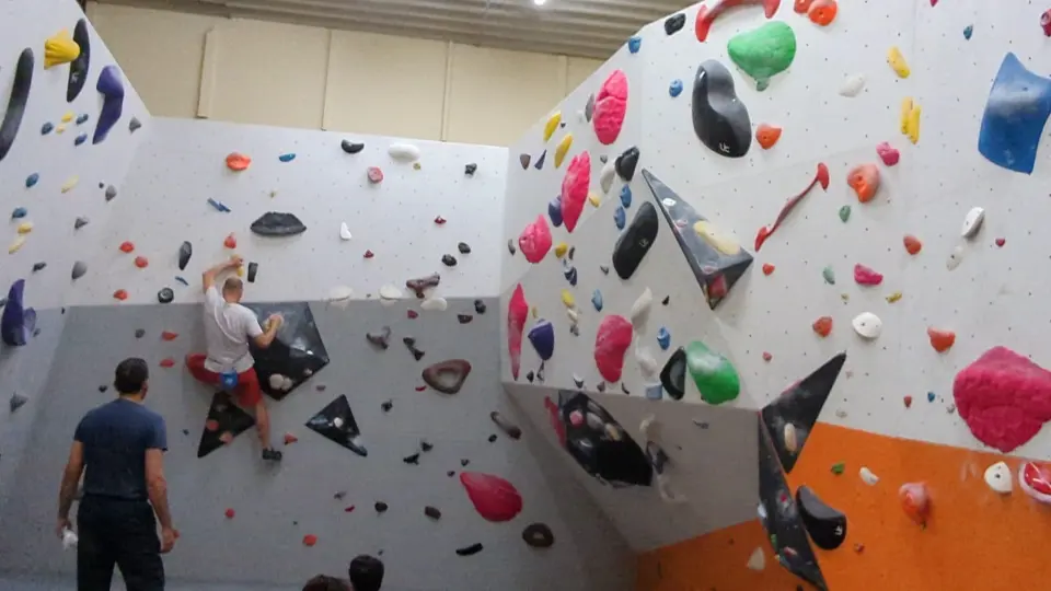 Climbers on the bouldering walls with orange and white panels