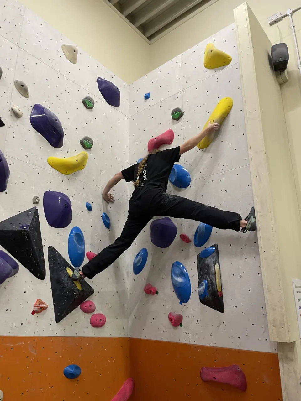 Climber bridging across a corner on the bouldering wall