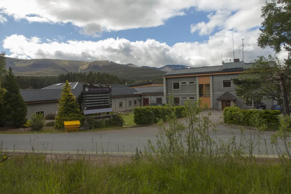 Glenmore Lodge buildings among pines with the Cairngorms behind