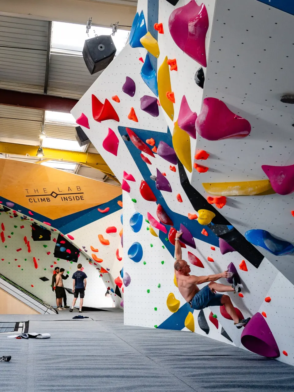 Climber on the volumes of the Titan competition wall
