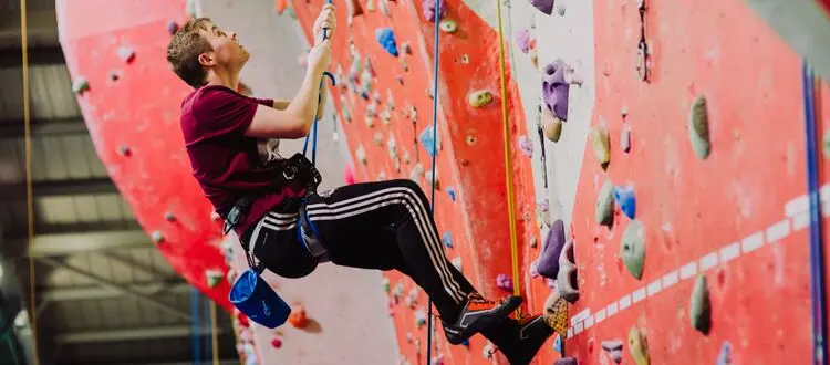 Climber on a top rope on the red and white wall at the Ozone Complex
