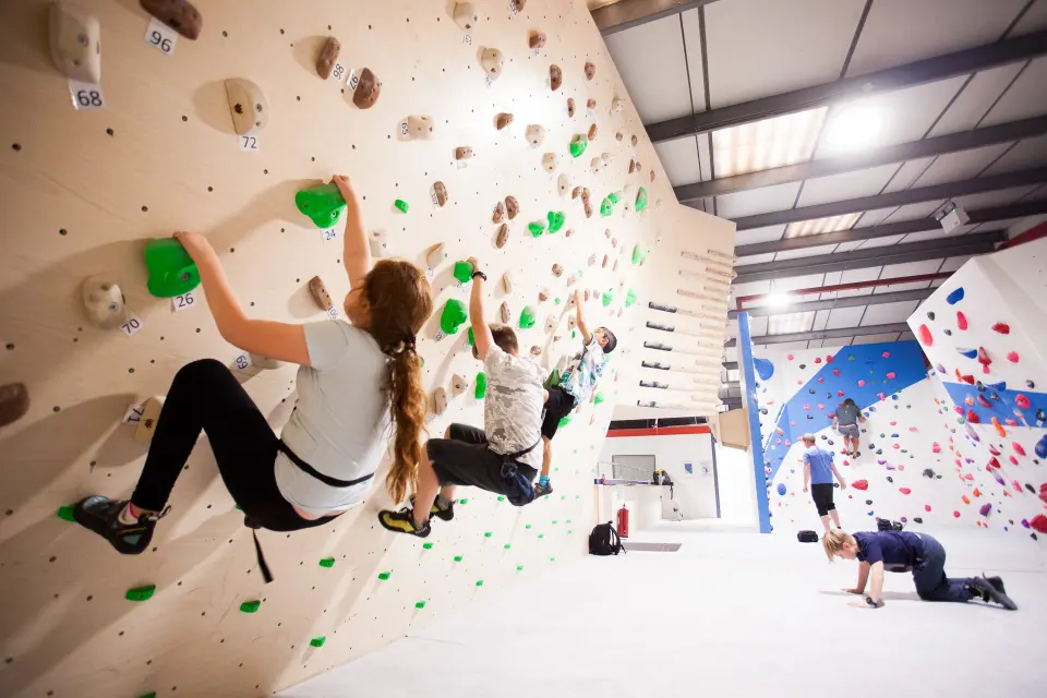 Climbers on a vertical bouldering wall with green holds