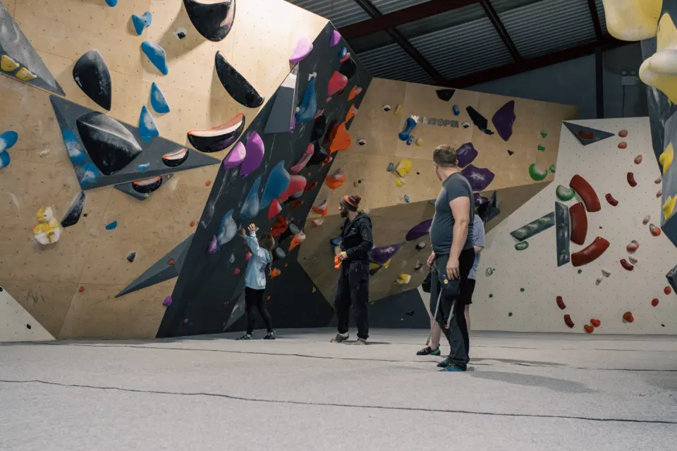 Climbers looking up at the black and wooden bouldering walls