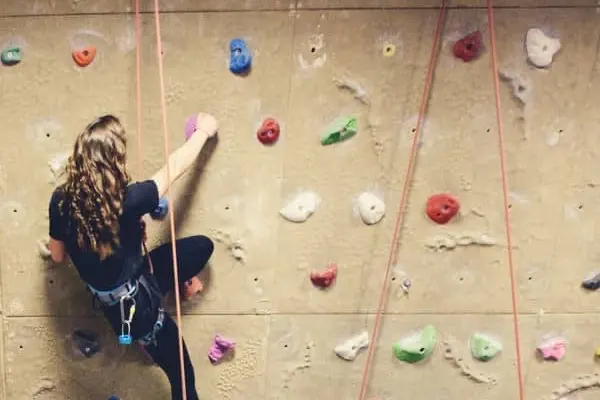 Climber on a top rope on the beige climbing wall