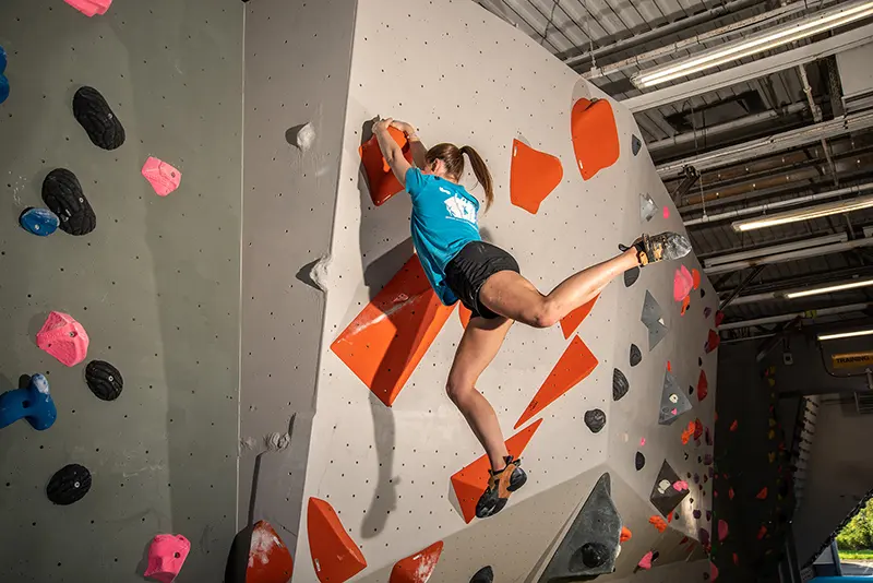 Climber on a white wall with orange volumes