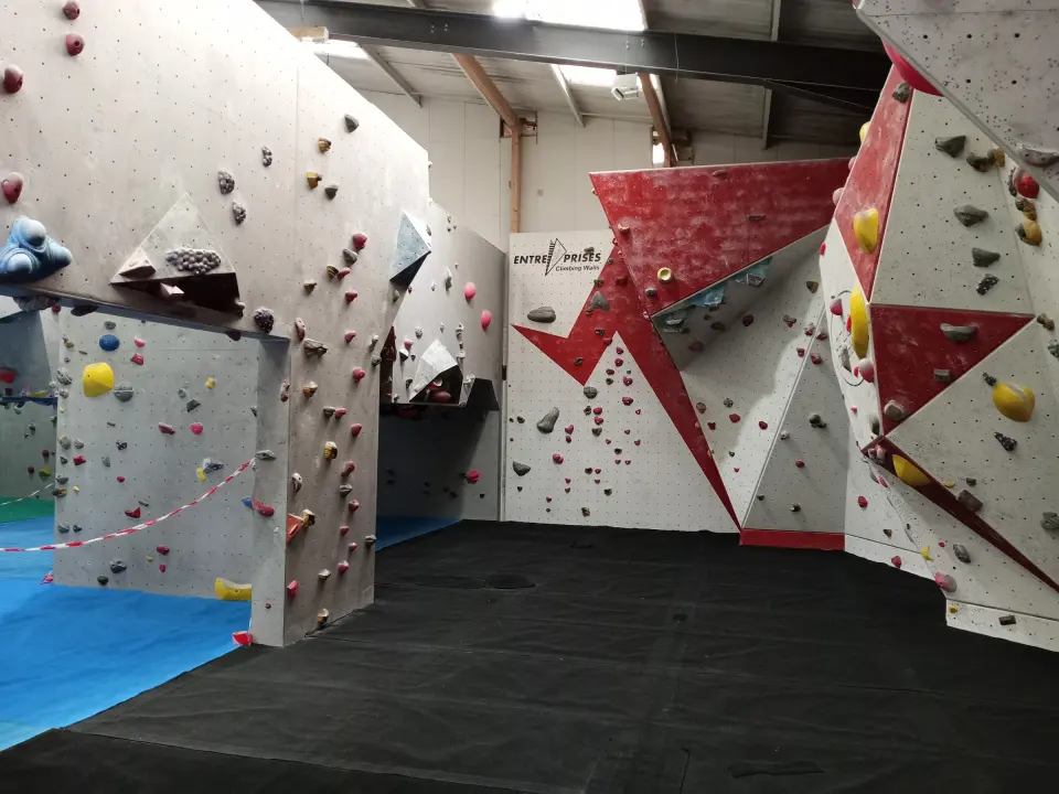 Bouldering hall with angled red panels and black matting