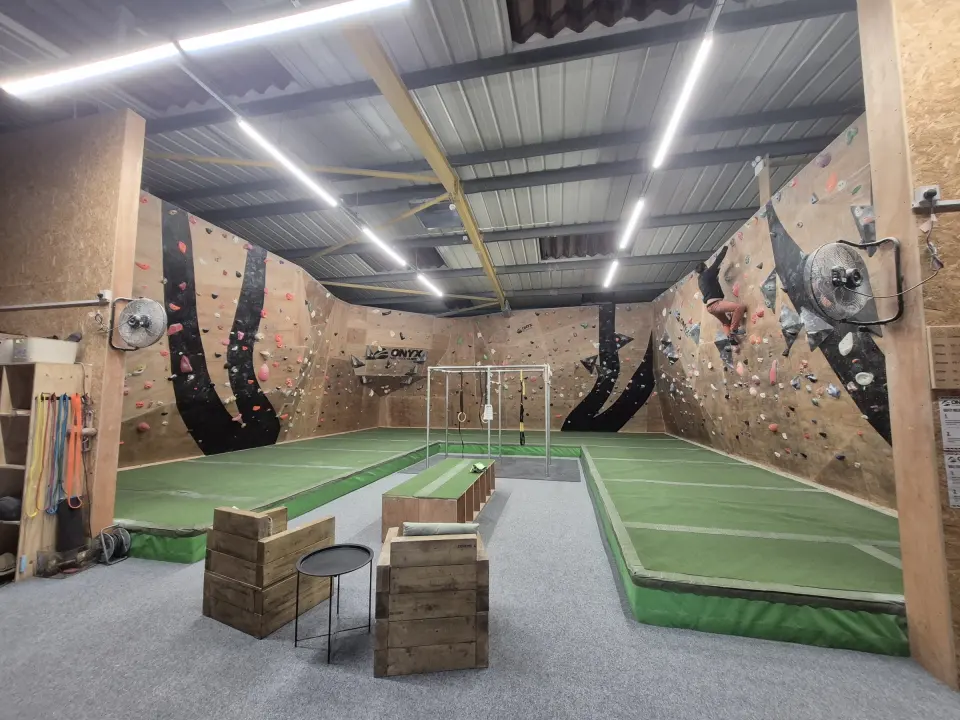 Plywood bouldering room with black swoosh panels and green matting