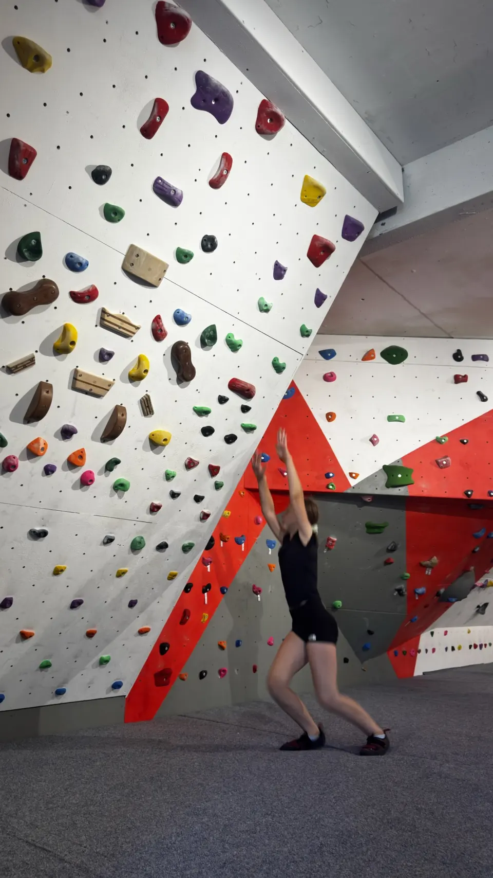 Climber reaching up a steep wall covered in holds