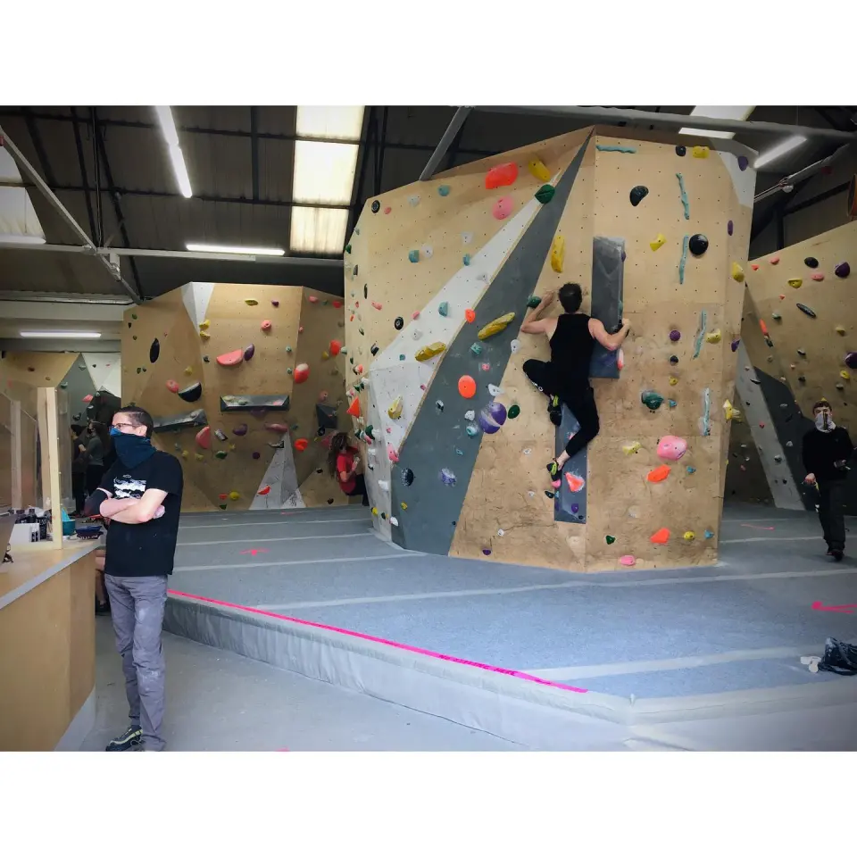 Bouldering hall with a tall wooden feature wall and matting
