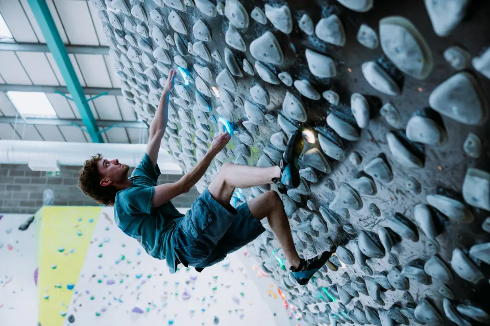Climber on a training board packed with grey holds
