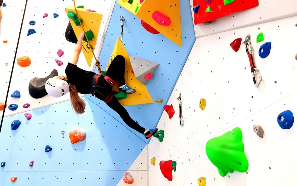 Climber on a top rope among yellow and red volumes