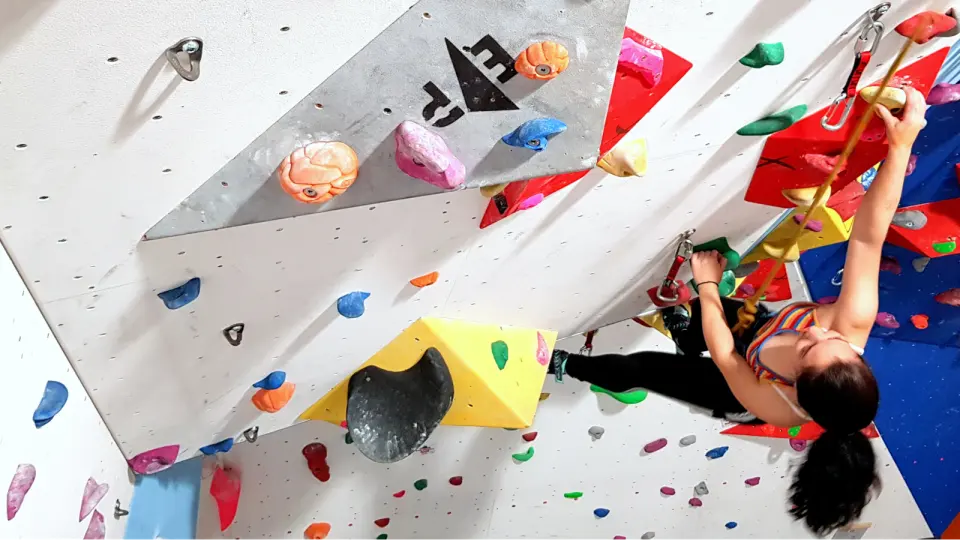 Climber moving past a grey volume on the main wall