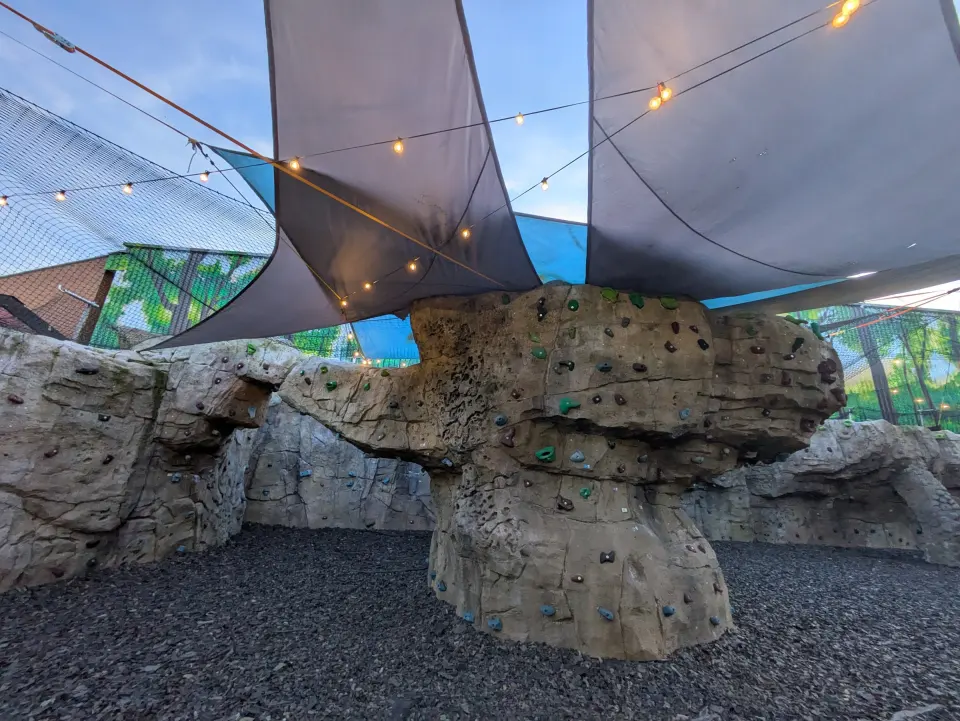 Mushroom-shaped artificial rock boulder under shade sails and festoon lights