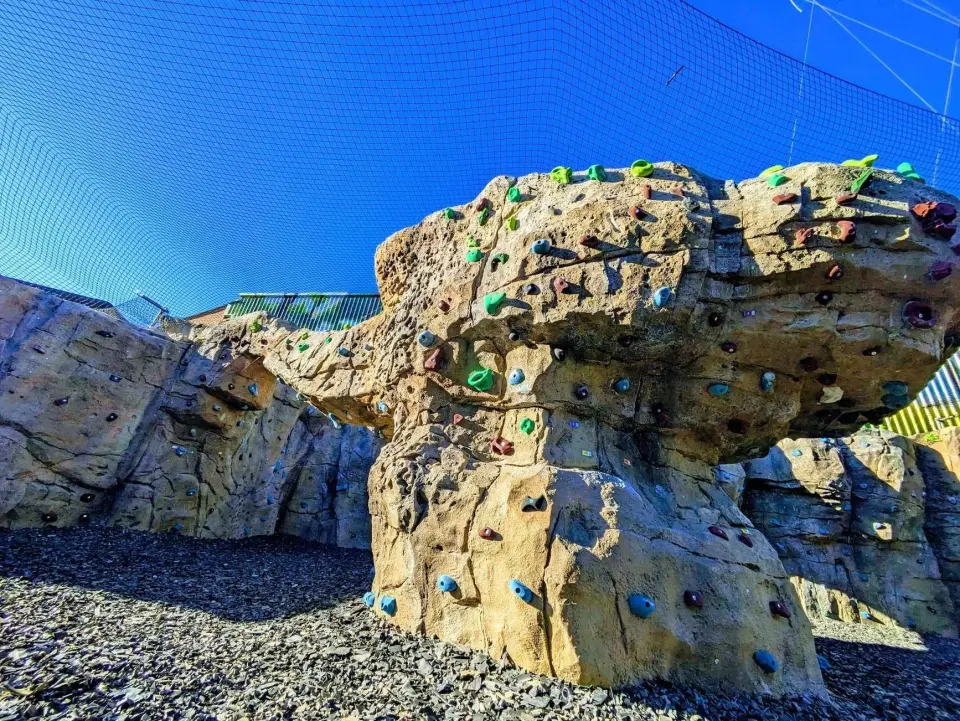 Overhanging artificial rock boulder on a gravel floor under netting