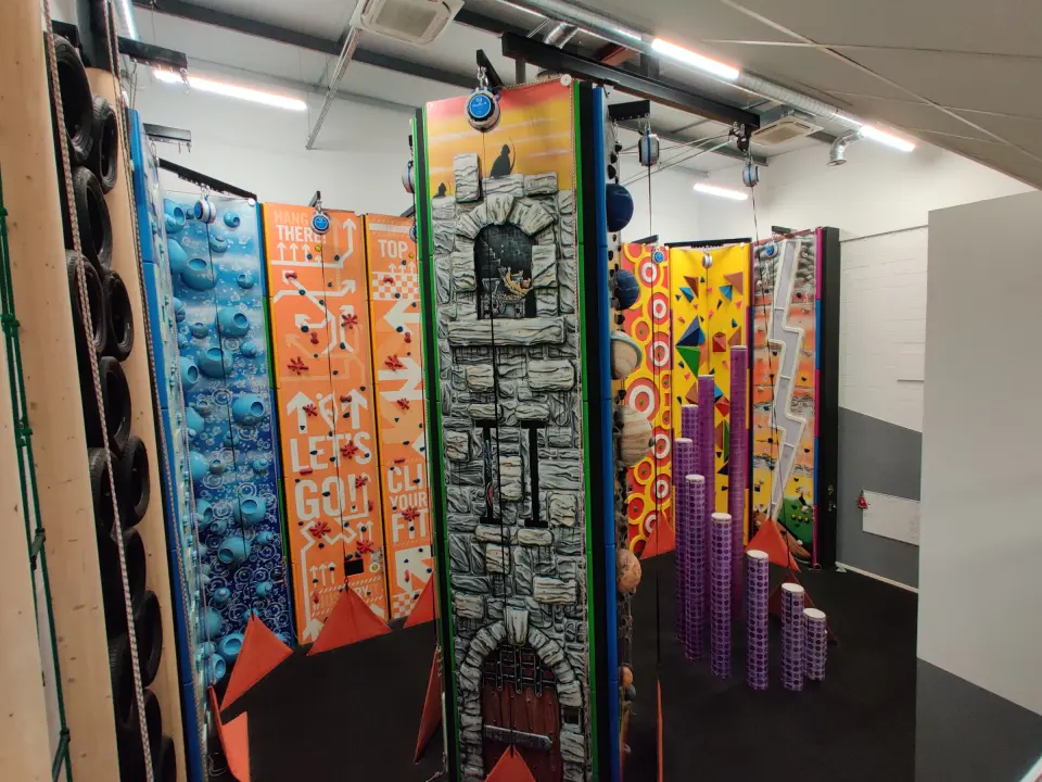 Row of themed auto-belay walls, including a castle tower and column challenge
