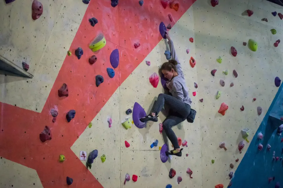 Climber on a purple problem on the red and cream wall