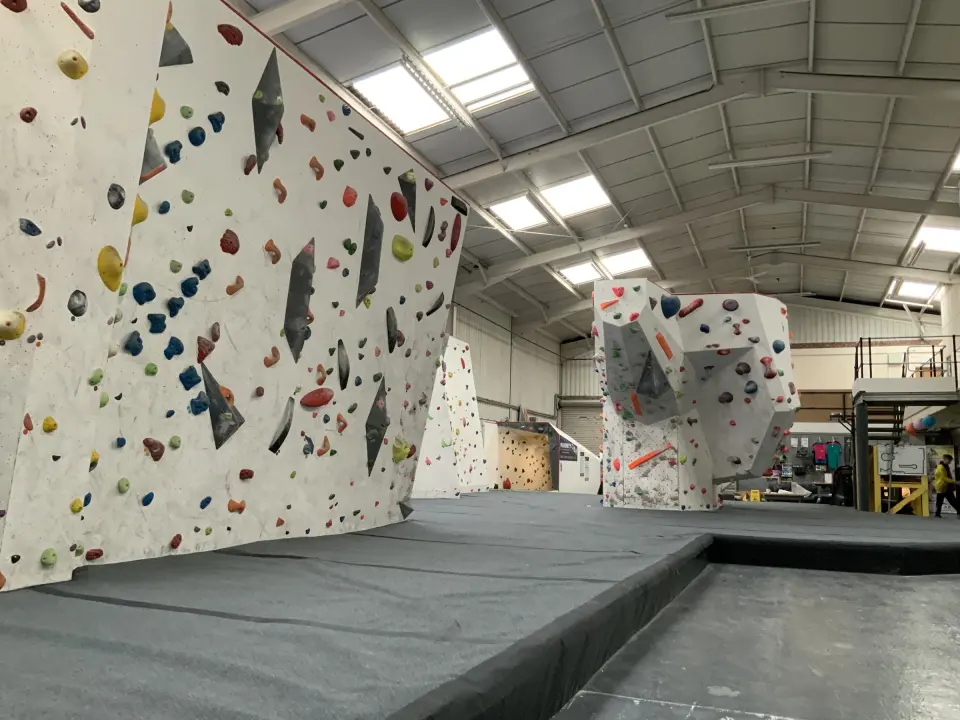 White bouldering walls with grey matting across the hall