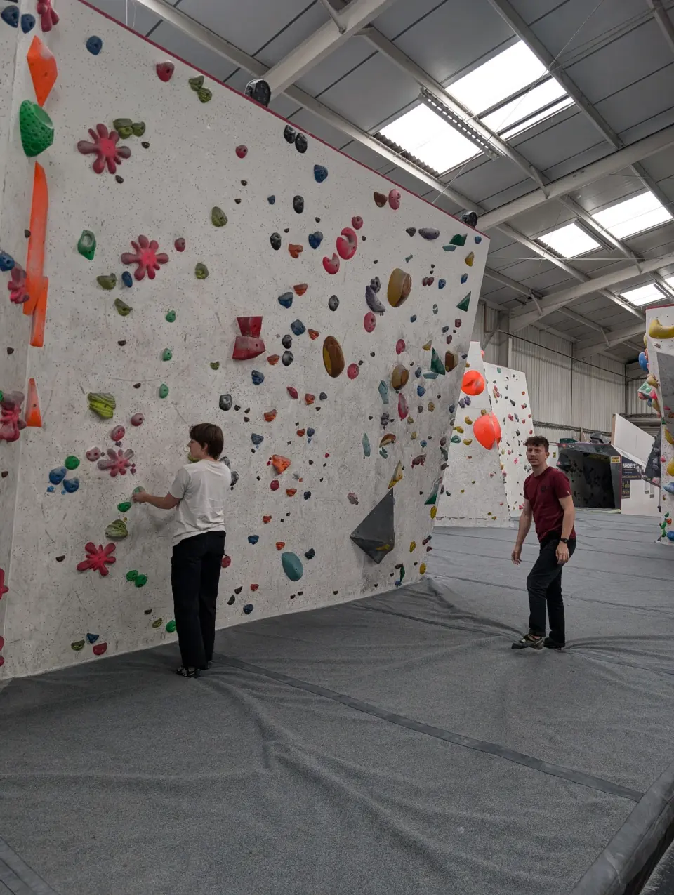 Tall white bouldering wall under the skylights