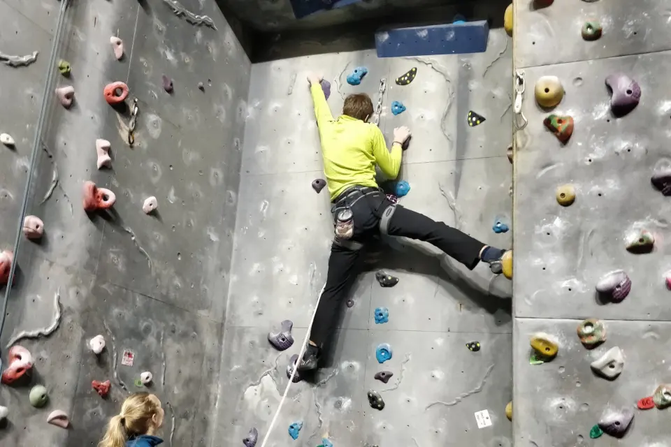 Climber on a top rope between grey textured wall panels
