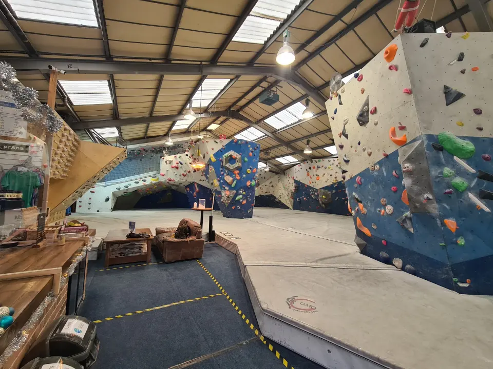 Bouldering hall with grey and blue walls under the skylit roof